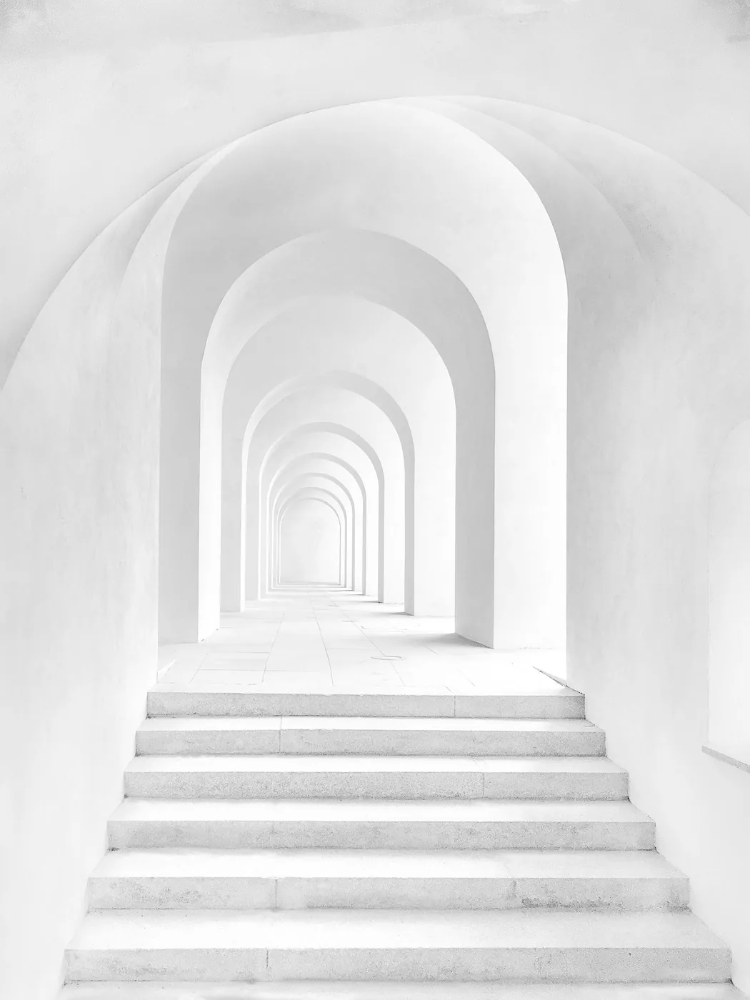 Perspective d’un passage aux arches blanches baigné de lumière