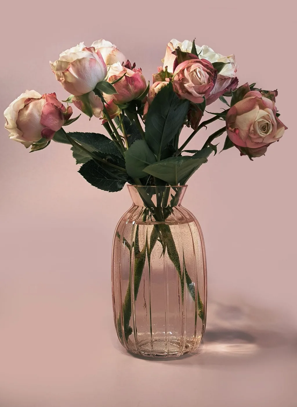 Roze en crèmekleurige rozen in een glazen vaas